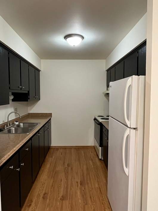 A kitchen with black cabinets and a white fridge.